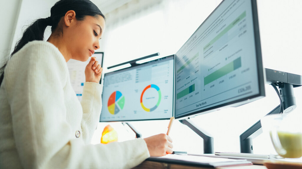Mulher analisando dashboards de dados em monitores no escritório