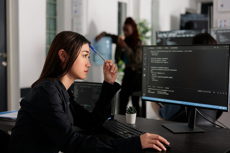 Profissional analisando código em monitor no escritório, representando o desenvolvimento de habilidades técnicas valorizadas pelo mercado na era da IA